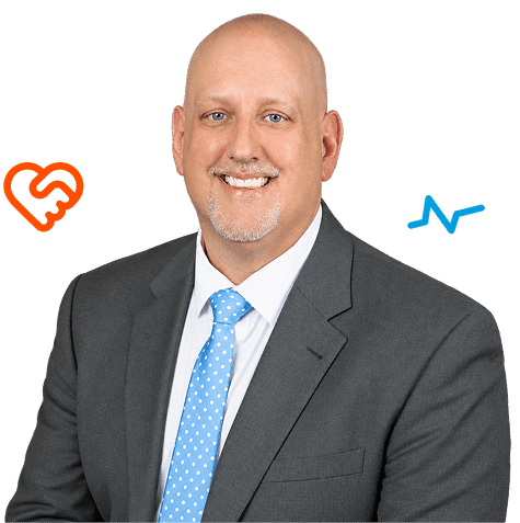 A smiling bald man in a grey suit and blue polka-dot tie with a heart-shaped handshake icon on his left and an EKG line icon on his right.