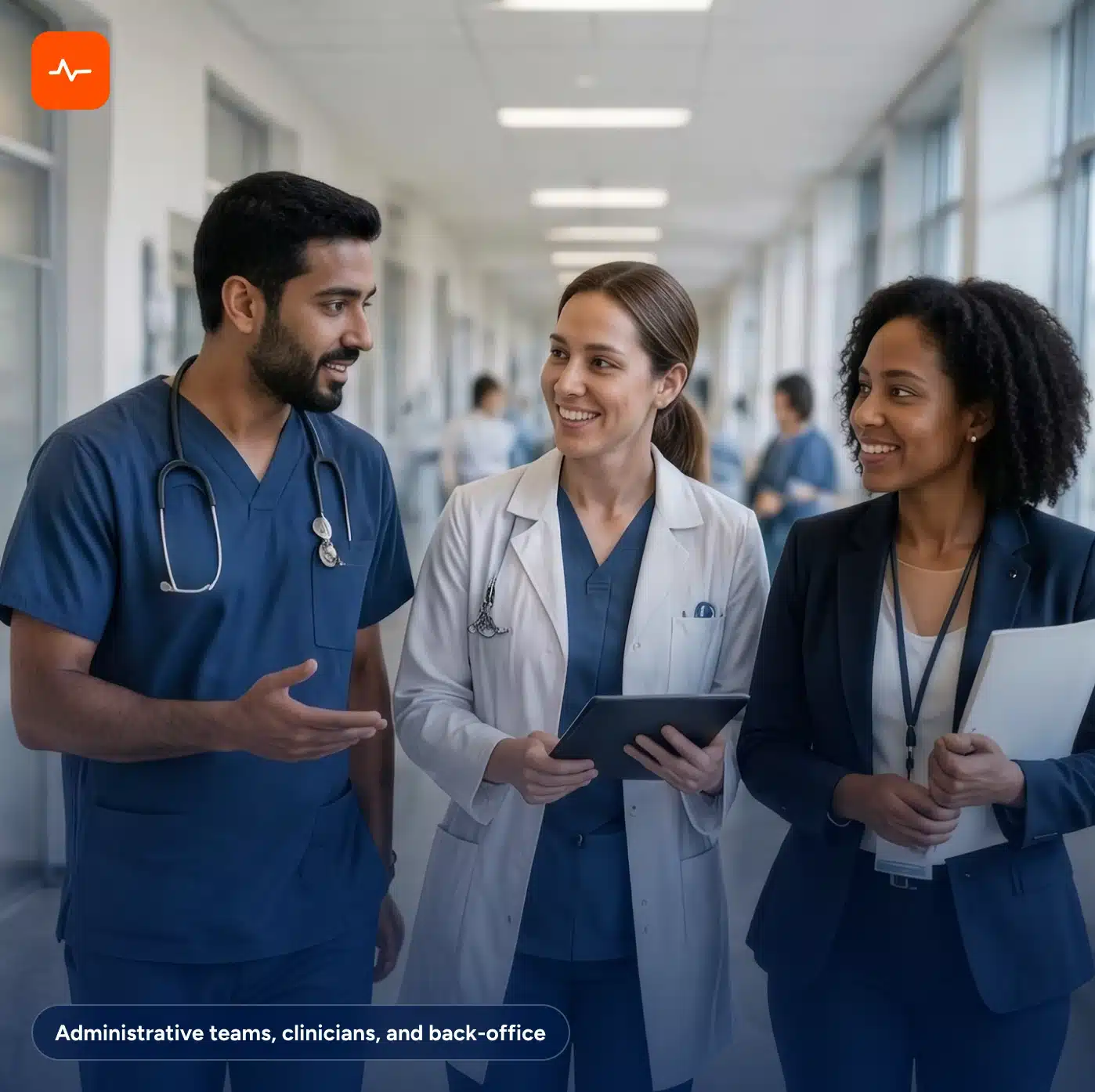 Two healthcare workers and an administrator walk down a hospital hallway while talking.